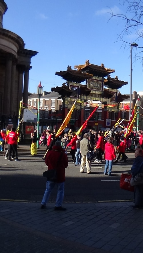 Chinese New Year Liverpool 2016 parade with flags with Chinese Arch in background at entrance to Chinatown 7th February 2016 photo 2