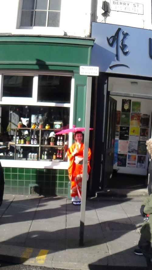 Chinese New Year Liverpool 2016 woman in costume with umbrella outside shop  7th February 2016